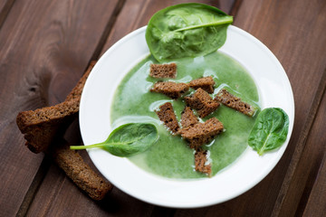 Spinach cream soup with croutons, close-up, studio shot