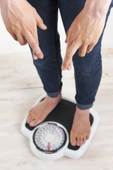 Woman Standing On Scales With Fingerrs Crossed