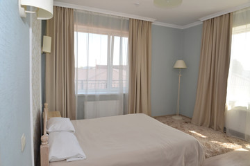 Interior of a double hotel room in light tones with two windows