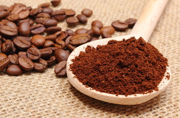 Ground coffee on wooden scoop and grains in background