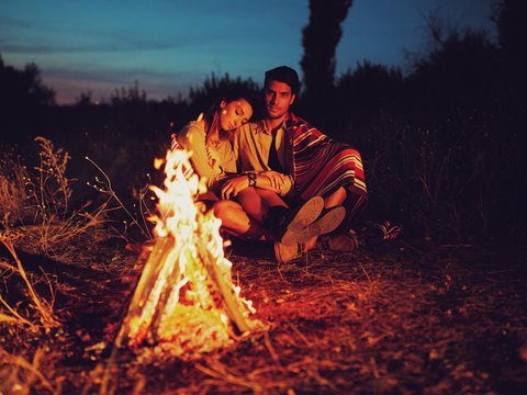 A Charming Couple Sitting Around The Campfire