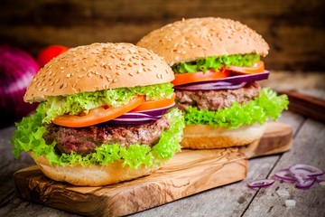 Two homemade burgers with lettuce, tomatoes and red onions
