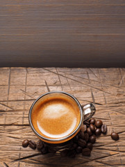 cup of espresso coffee with coffee crop beans on wood back