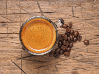 cup of espresso coffee with coffee crop beans on wood back