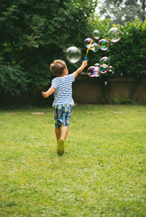 Cute 5 year old boy running making soap bubbles