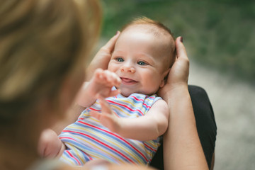 Adorable smiling baby held in his mother’s lap
