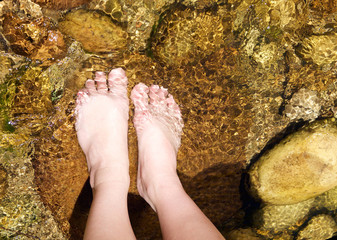 Pair of female feet standing in a stream