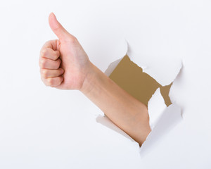 Hand with thumb up through a hole in paper