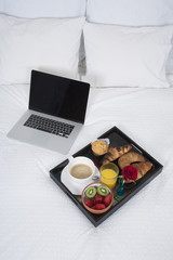 breakfast and laptop on bed