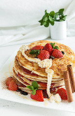 White plate full of pancakes with raspberries strawberries blueb