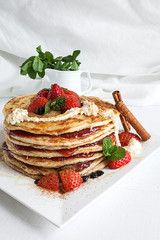 White plate full of pancakes with raspberries strawberries blueb