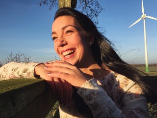 Frau mit Windrad im Hintergrund lächelt