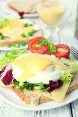 Fototapeta na wymiar Toast with egg Benedict and tomato on plate on wooden table