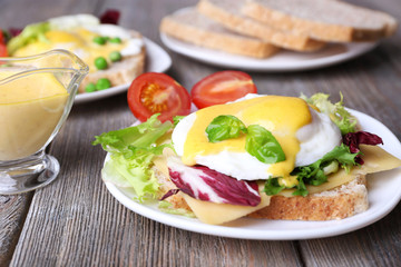 Toast with egg Benedict and tomato on plate on wooden table
