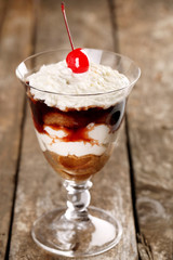 Tasty tiramisu dessert in glass, on wooden background