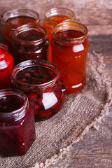 Homemade jars of fruits jam on rustic wooden background