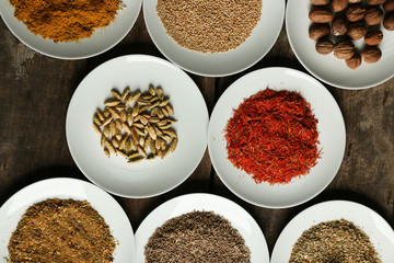 Different spices on plates, on old wooden table
