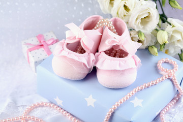 Fototapeta na wymiar Pink baby boots with gift close-up