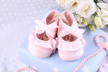 Fototapeta na wymiar Pink baby boots with gift close-up