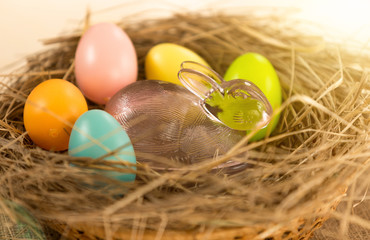 Closeup shot of colorful Easter eggs and glass rabbit lying in n