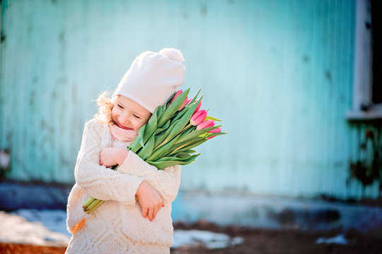 happy child girl with bouquet of tulips in early spring