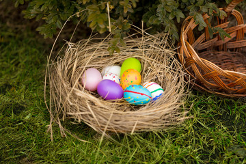 Closeup shot of colored Easter eggs lying in basket on yard