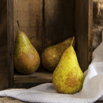 Pears in rustic kitchen setting with wooden box and hessian sack