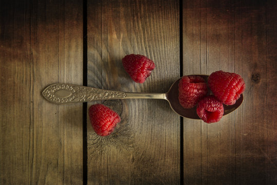 Raspberries in rustic kitchen setting with wooden background wit