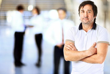 Portrait of handsome confident young businessman standing arms crossed