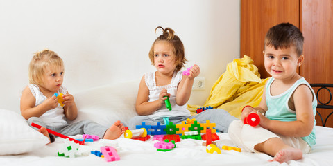  girls and a boy playing on  big bed.