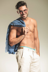 young fashion man holding his shirt on the shoulder