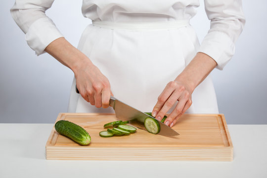 Cook's hands cutting fresh cucumber