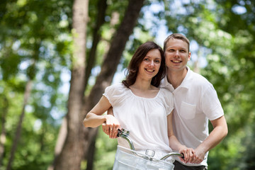 Happy young couple walking with bicycle