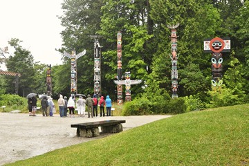 People who watch Totem Pole at Stanley Park during rainy day