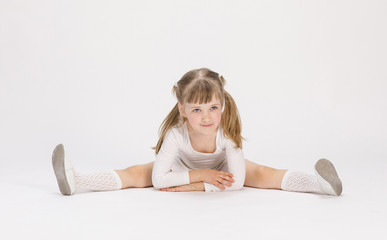 Pretty little girl sitting on the floor and doing exercise