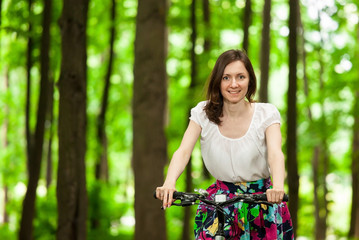 Fototapeta premium Happy young girl on bicycle in summer park