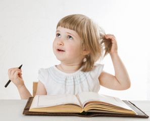 Smiling little girl holding a pen and looking up