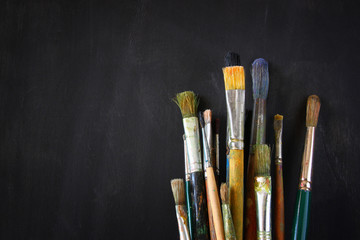 paint brushes in jar over blackboard background