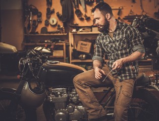 Mechanic building vintage style cafe-racer motorcycle  