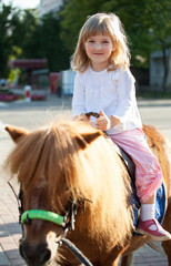 Happy smiling little girl  on a pony