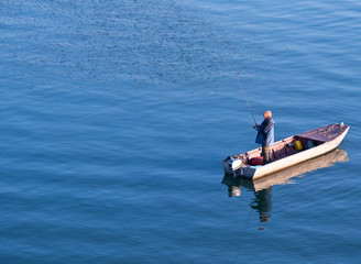 Fisherman standing on a boat and fishing in sea