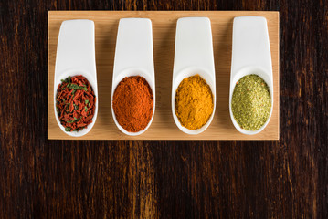 Colorful spices on brown wooden table top view