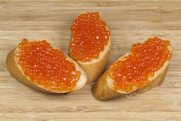 Sandwiches with red caviar on a wooden board