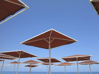 Red metallic parasol beach umbrellas over blue sky