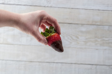 Hand holding a strawberry with chocolate