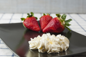 Strawberries and cream on a black plate