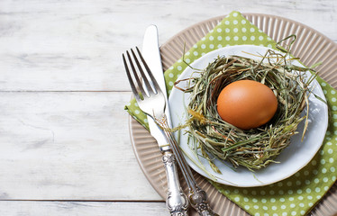 Easter table setting with chicken eggs in nest