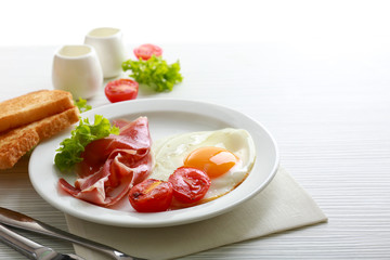 Bacon and eggs on color wooden table background