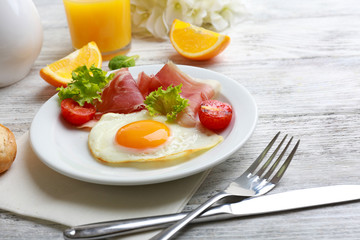 Bacon and eggs on color wooden table background.
