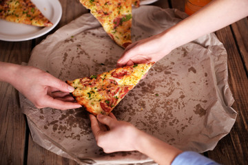 Friends hands taking slice of pizza